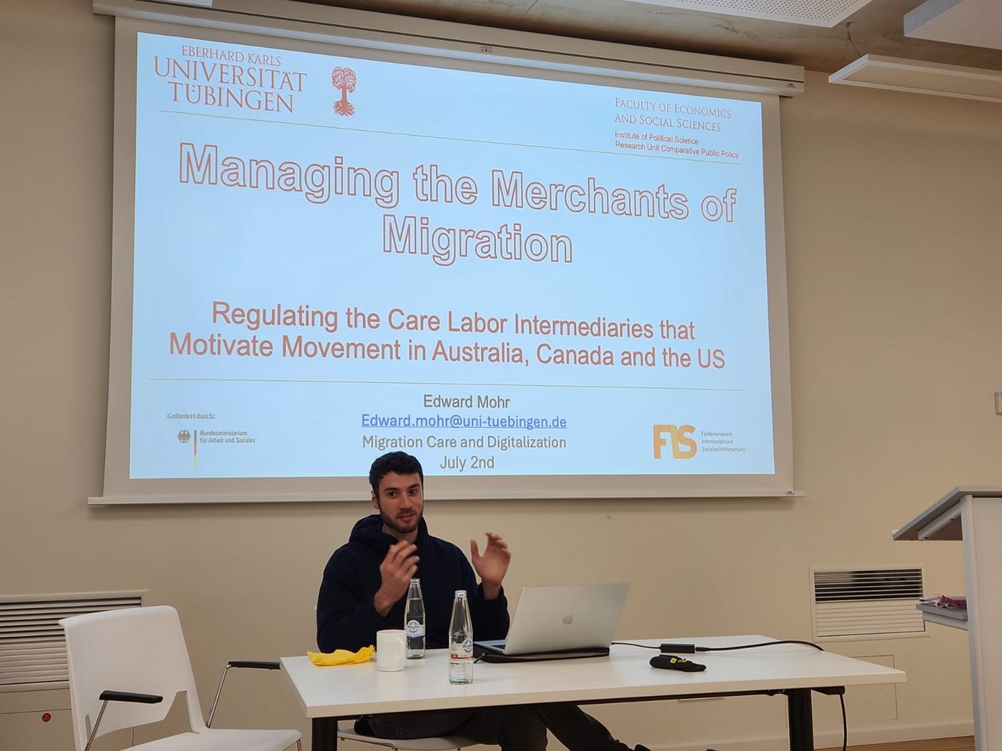 Man speaking in front of a presentation screen.