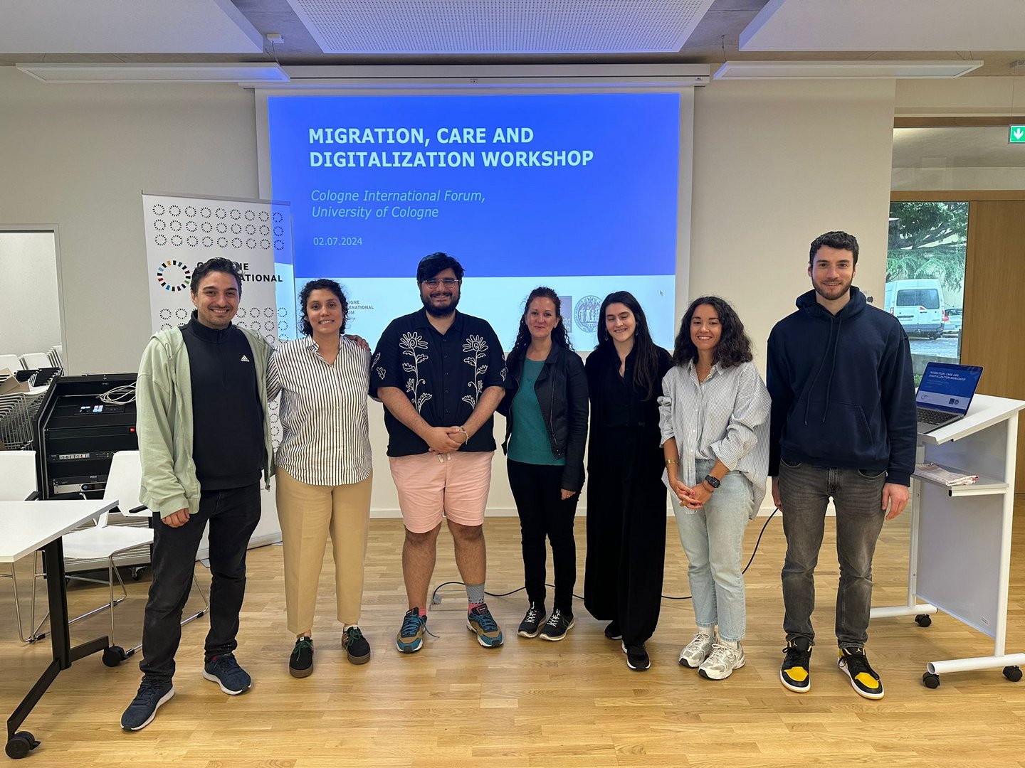 A group of people standing in front of a screen, which reads "Gender, Migration and Digitalization of Care Work".